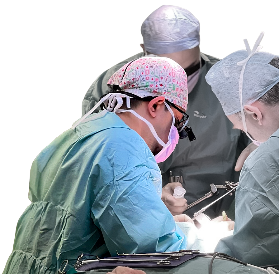 Team of surgeons in blue and green scrubs performing surgery with specialized lighting and medical equipment.